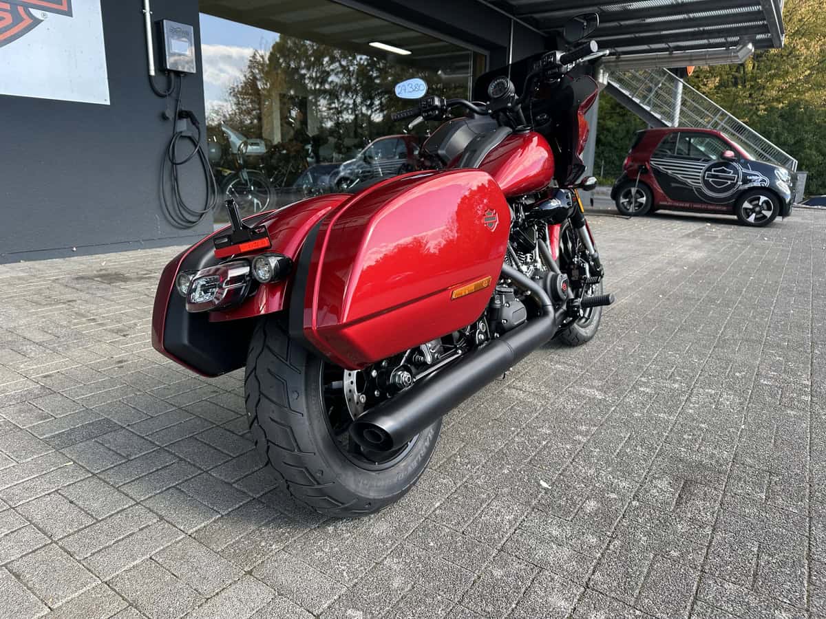 Harley-Davidson Motorrad mit Seitenkoffer in Rot, vor dem Harley-Shop.